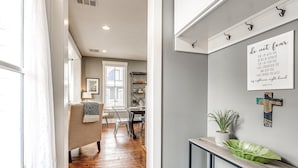 A hallway with a dining area, a sofa, a console table with a plant, and a motivational quote on the wall. - Carlton Landing-Goose Bay (Carlton Landing)
