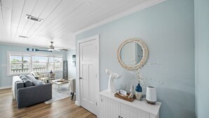 Una sala de estar moderna con un sofá, una mesa de centro y un espejo decorativo sobre una consola blanca.