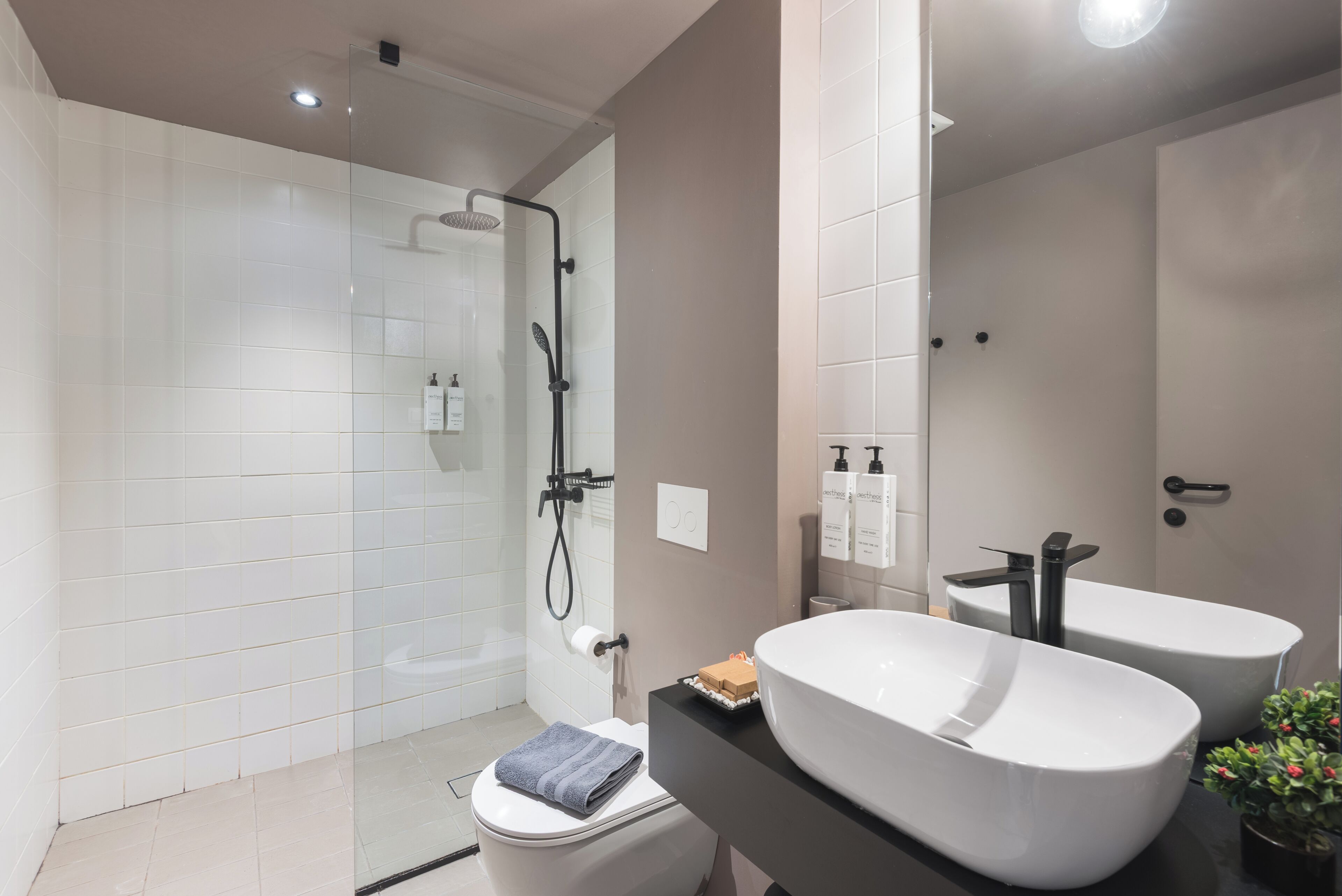Un baño moderno con ducha envuelta en vidrio, inodoro y tocador doble.