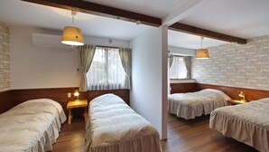 Una habitación con cuatro camas individuales, piso de madera y pared de ladrillo.