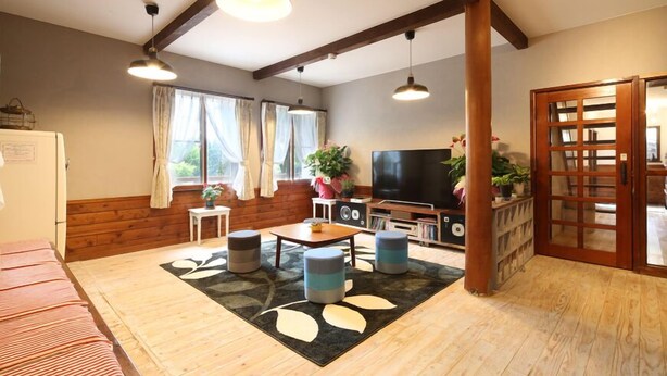 Una sala de estar acogedora con piso de madera, un sofá, un televisor y un comedor con una mesa y sillas.