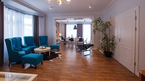Un vaste espace de vie doté d’un plancher en bois, de fauteuils bleus, d’une table basse ronde et d’une table à manger avec des chaises.