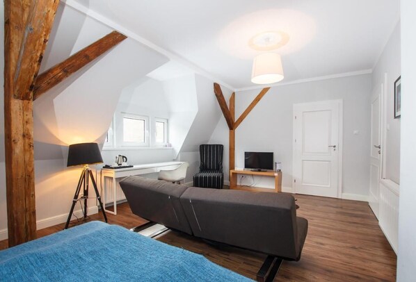 An attic room with a bed, a desk, a chair, a TV, and a lamp. - A small but grand hotel for private use (Pieszyce)