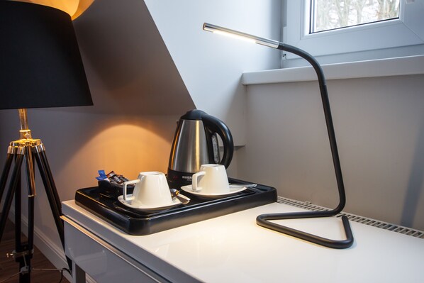 A hotel room with a desk, a lamp, a kettle, and two cups on a tray. - A small but grand hotel for private use (Pieszyce)
