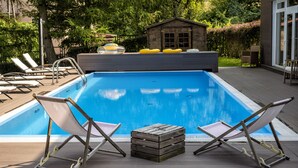 Une piscine avec des chaises longues et une terrasse en bois.