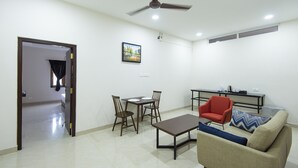 Una sala de estar moderna con comedor, sofá, un sillón rojo y un ventilador de techo.