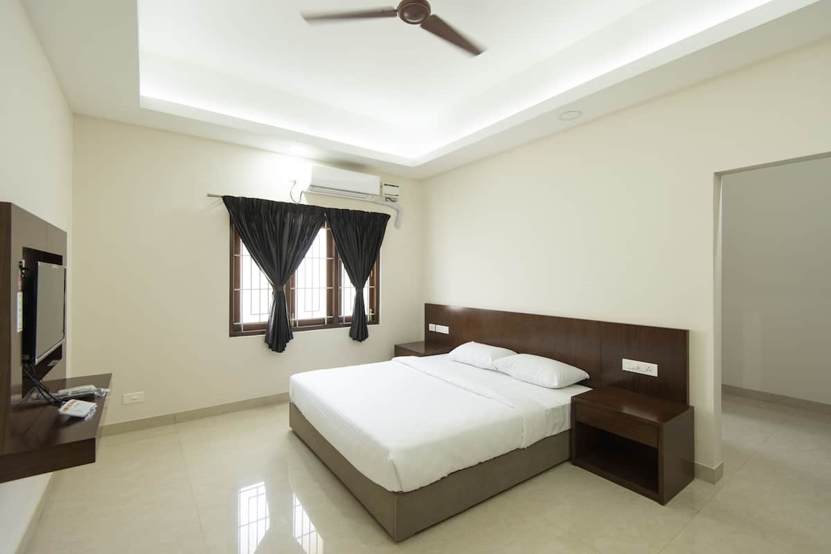 Une chambre moderne avec un grand lit, une table de chevet, un téléviseur et un ventilateur de plafond.