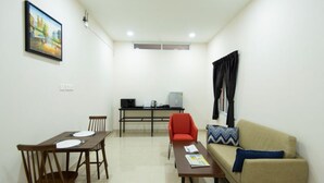 Una sala de estar con una mesa de comedor, sillas, un sofá y una televisión.