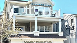En tvåvåningsbyggnad med en balkong, en skylt med texten ”Golden Nails N’ Spa” och ett telefonnummer.