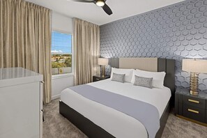 A modern hotel room with a large bed, a desk, and a view of the outdoors.
