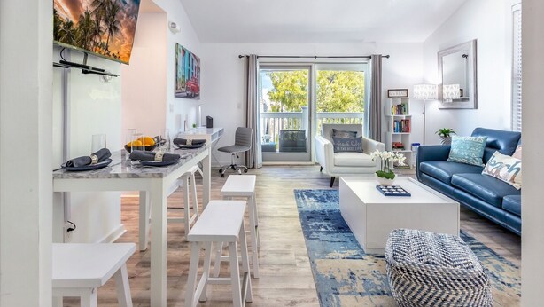 Uma sala moderna com área de jantar, um sofá, uma mesa de centro e uma varanda com vista.