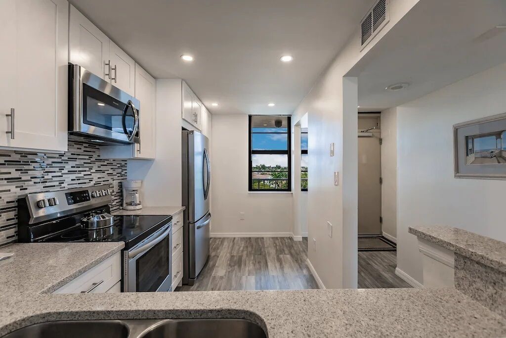 Una cocina moderna con electrodomésticos de acero inoxidable, salpicadero de azulejos y ventana con vistas al exterior.