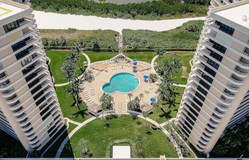Un immeuble de grande hauteur doté d’une piscine centrale, entourée d’espaces de détente et de verdure.