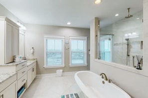 Een moderne badkamer met een ruim bad, een aparte douche en een wastafel met spiegel.