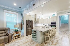 A modern kitchen with a central island, built-in appliances, and a dining area with bar stools. - Casa Bella 5 Bedroom Home by RedAwning (Navarre)