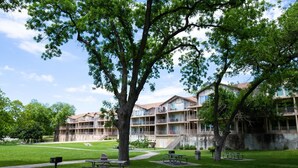 Ein mehrstöckiges Hotel mit Balkonen, einem grünen Innenhof und Picknicktischen.