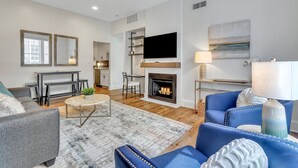 A modern living room with a fireplace, a dining area, and a kitchen visible through an open door. - Unbeatable Location in Heart of Historic Savannah by Lucky Savannah (Savannah)