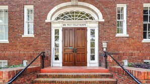 A brick building with a large wooden double door, numbered 101 West Oglethorpe, and a set of brick steps leading up to it. - Unbeatable Location in Heart of Historic Savannah by Lucky Savannah (Savannah)