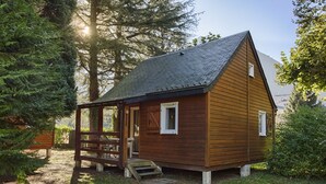 A wooden cabin with a porch, a small table, and a bench. - 6-person chalet (Laruns)