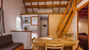 A cozy room with a wooden dining table, chairs, a sofa, and a staircase. - 6-person chalet (Laruns)