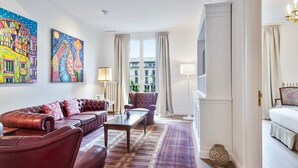 Ein modernes Wohnzimmer mit einer Ledersofa, einem gemusterten Teppich und Kunstwerken an den Wänden.