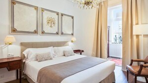 Ein Hotelzimmer mit einem großen Bett, einer Kristallleuchtre und gerahmten Kunstwerken an der Wand.