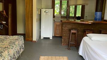 Una habitación compacta con cama, kitchenette pequeña y zona de comedor.
