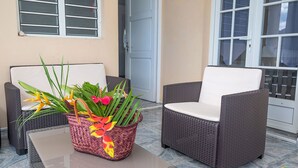 Un patio con mobiliario de mimbre, una cesta tejida con flores y un suelo de baldosas.