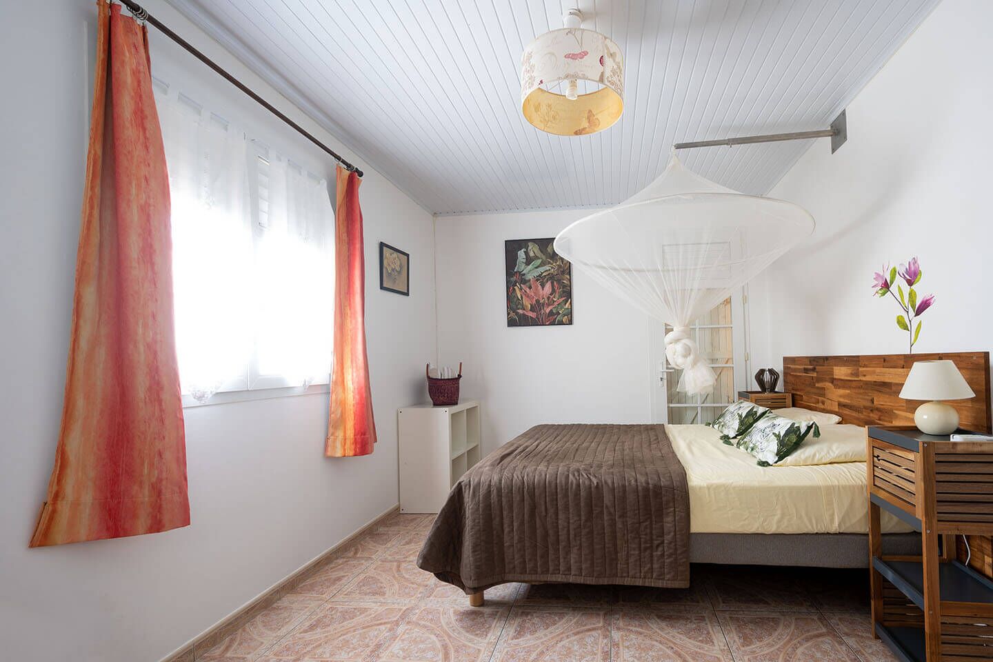 A bedroom with a bed, a nightstand, a lamp, and a window with curtains.