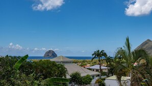 Un resort tropical con vista al océano y una montaña destacada al fondo.