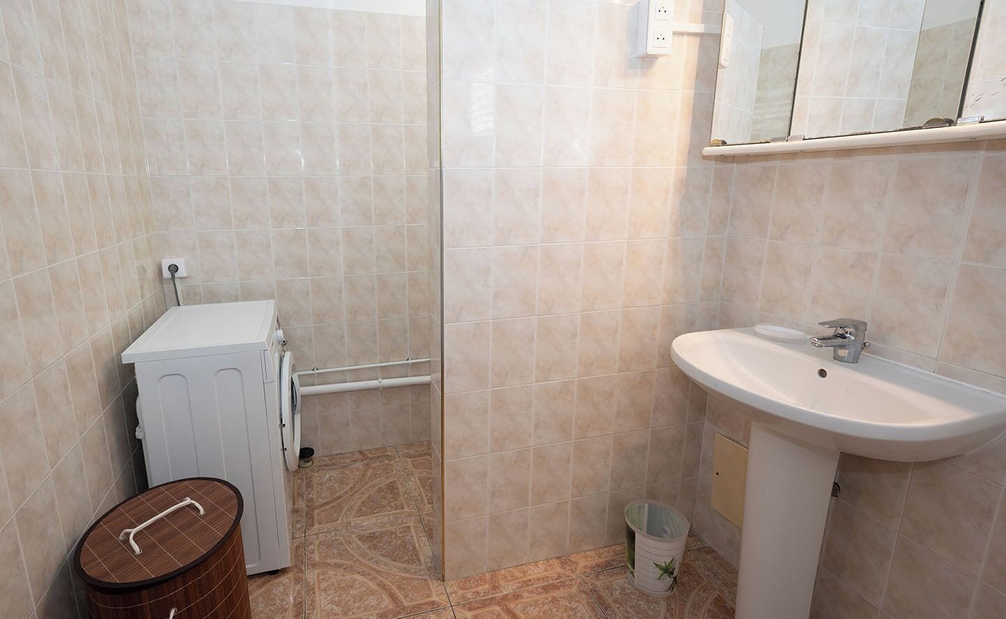 Un bagno con lavatrice, lavandino e cestino.