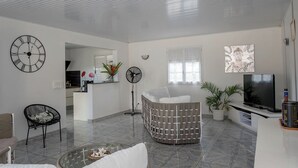 Una sala de estar moderna con un sofá, un televisor, un reloj y un ventilador.