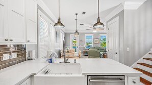 A modern kitchen with white cabinetry, a large island with a sink, and pendant lighting.