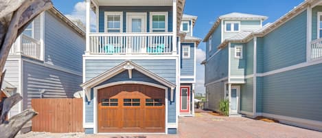 A two-story house with a front garage, a balcony, and a red door.