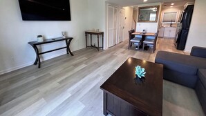 Una sala de estar moderna con un televisor de pantalla plana, una mesa de centro de madera oscura y un sofá azul.