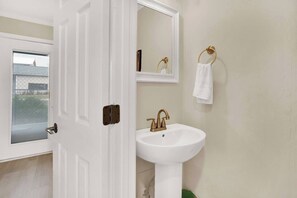 Une salle de bain avec une porte blanche, un lavabo blanc et un miroir.