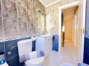 Et badeværelse med toilet, håndvask og bruser.