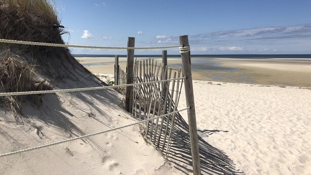 Una playa arenosa con un cerco de madera y una barrera de cuerda.