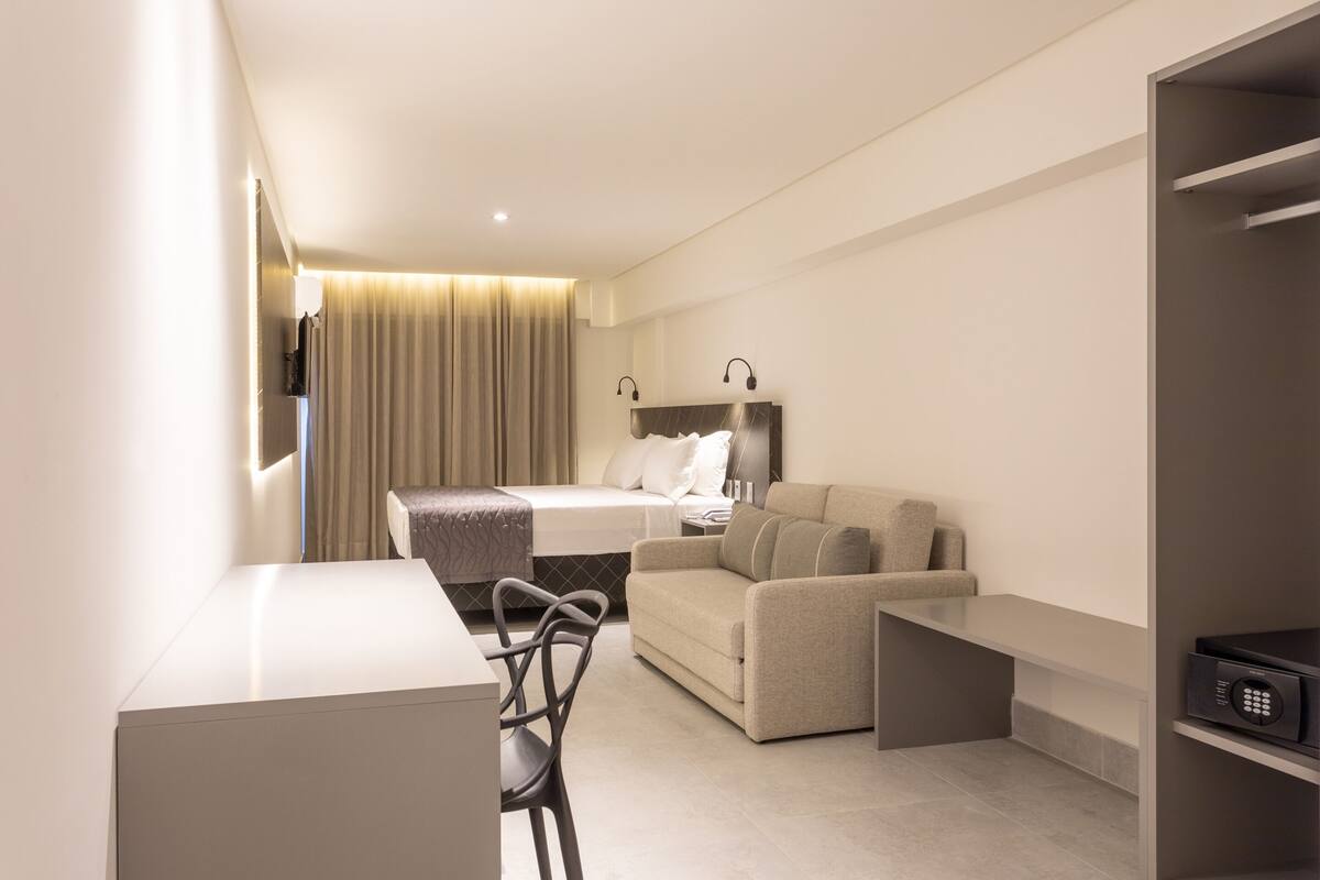 Una habitación de hotel moderna con cama, sofá, escritorio y televisor.