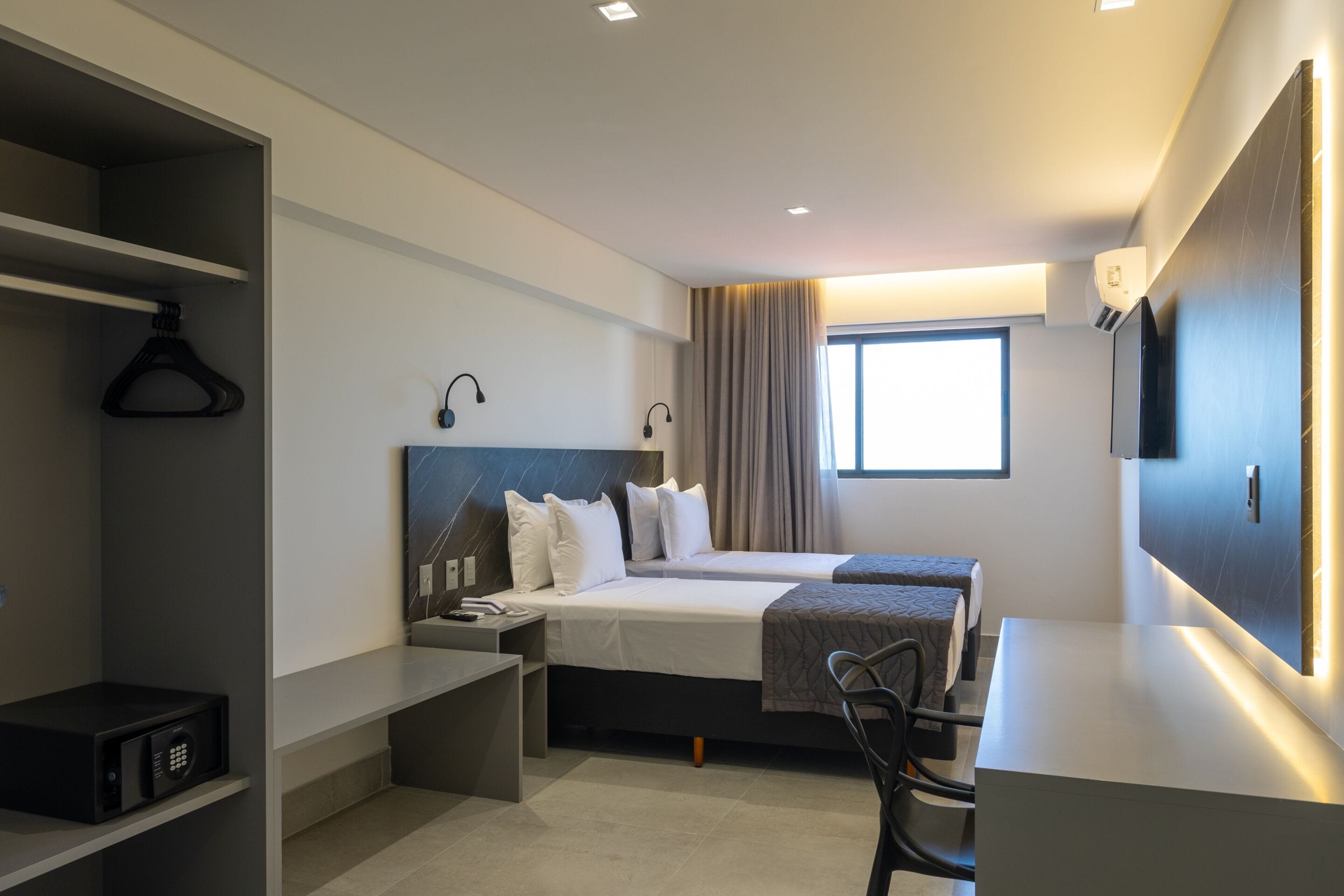 Una habitación de hotel moderna con una cama grande, un escritorio y un televisor.