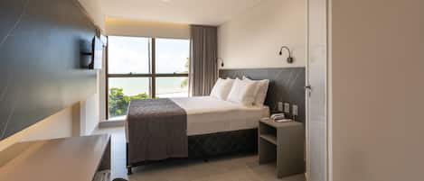 Habitación de hotel moderna con una cama grande, un escritorio y vistas al océano.