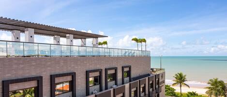 Un hotel moderno con un balcón de cristal con vistas a la playa.