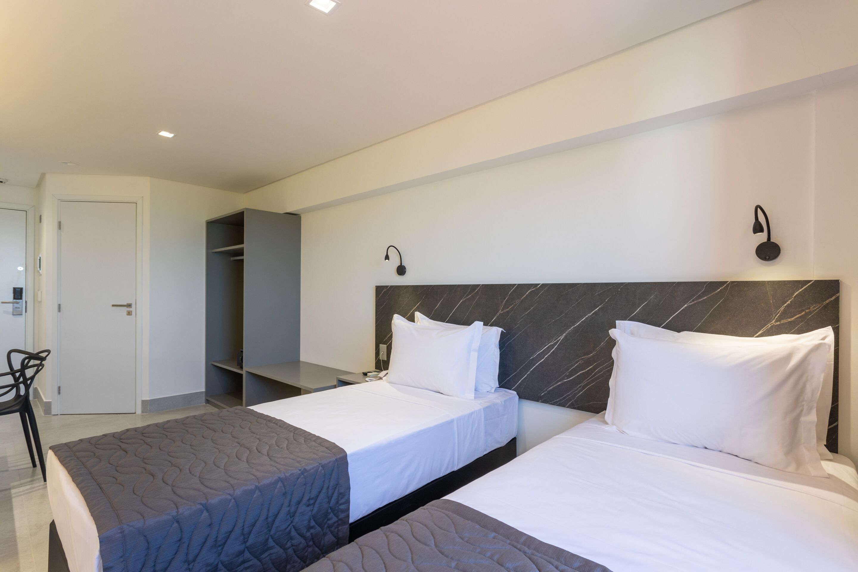 Habitación de hotel con dos camas, un escritorio y un armario.