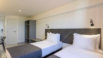 Habitación de hotel con dos camas, un escritorio y un armario.
