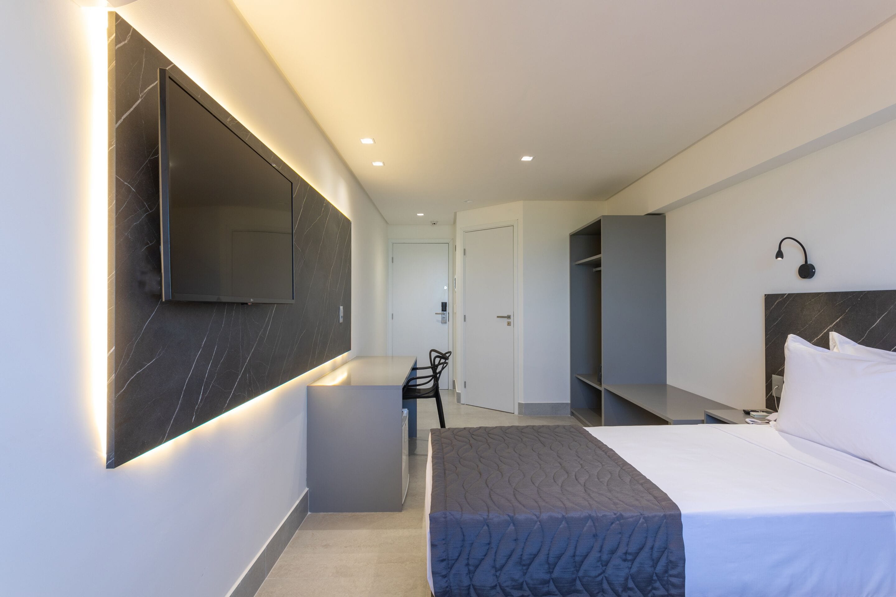 Una habitación de hotel moderna con una cama grande, un escritorio y un armario.