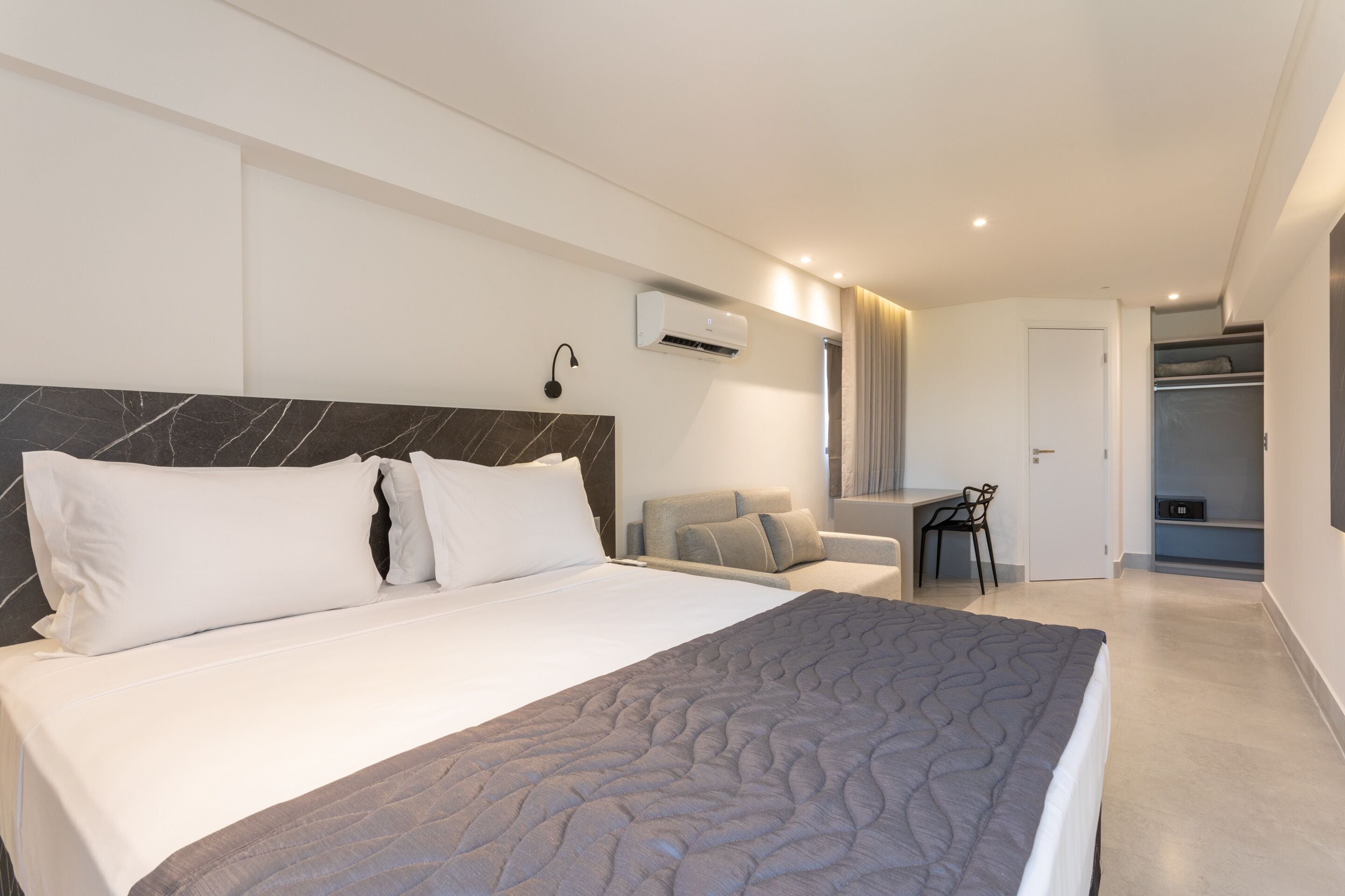 A modern hotel room with a large bed, a desk, and a seating area.