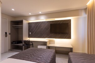 Una habitación de hotel moderna con una cama grande, un escritorio, una silla y televisión integrada.