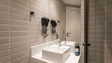 Casa de banho moderna com duas pias, um secador de cabelo e um frasco de sabonete líquido.