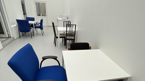 A modern meeting room with a white table, blue chairs, and a microwave. - The Old Factory - Hostel (Copenhagen)