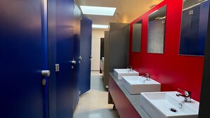 A modern bathroom with blue lockers, red walls, and multiple sinks. - The Old Factory - Hostel (Copenhagen)